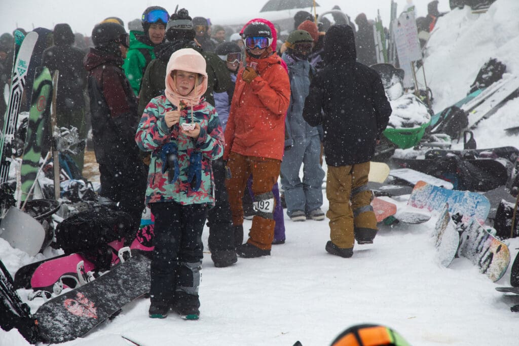 Josie Weeks eats a chocolate-covered strawberry as crowds wait behind her chatting and eating.