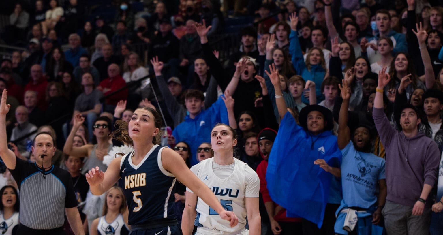 Western's fans react as Maddy Grandbois hits a 3-pointer as both players watch to see if the ball goes through.