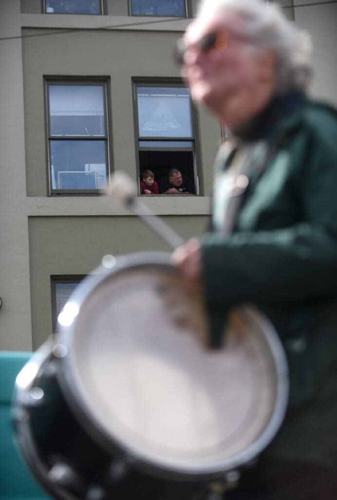 People watch from a window of the Washington Grocery Building as the parade moves down East Chestnut Street.