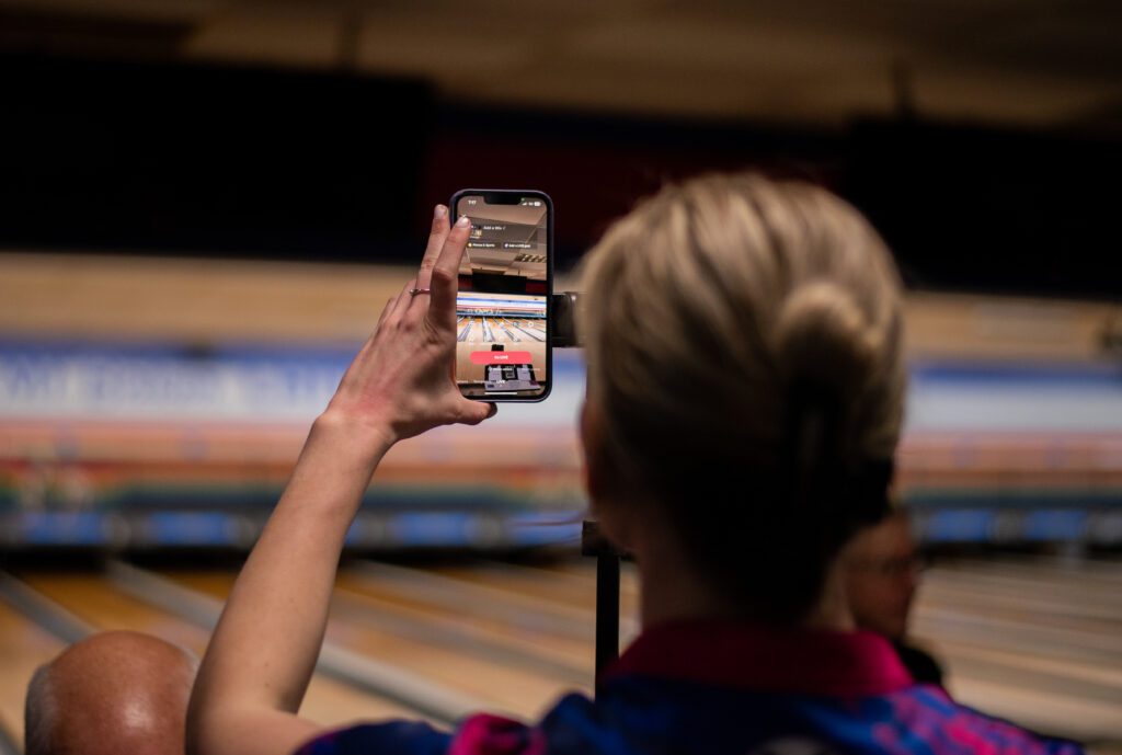 A young woman sets up an iPhone to live stream on TikTok in a bowling alley.