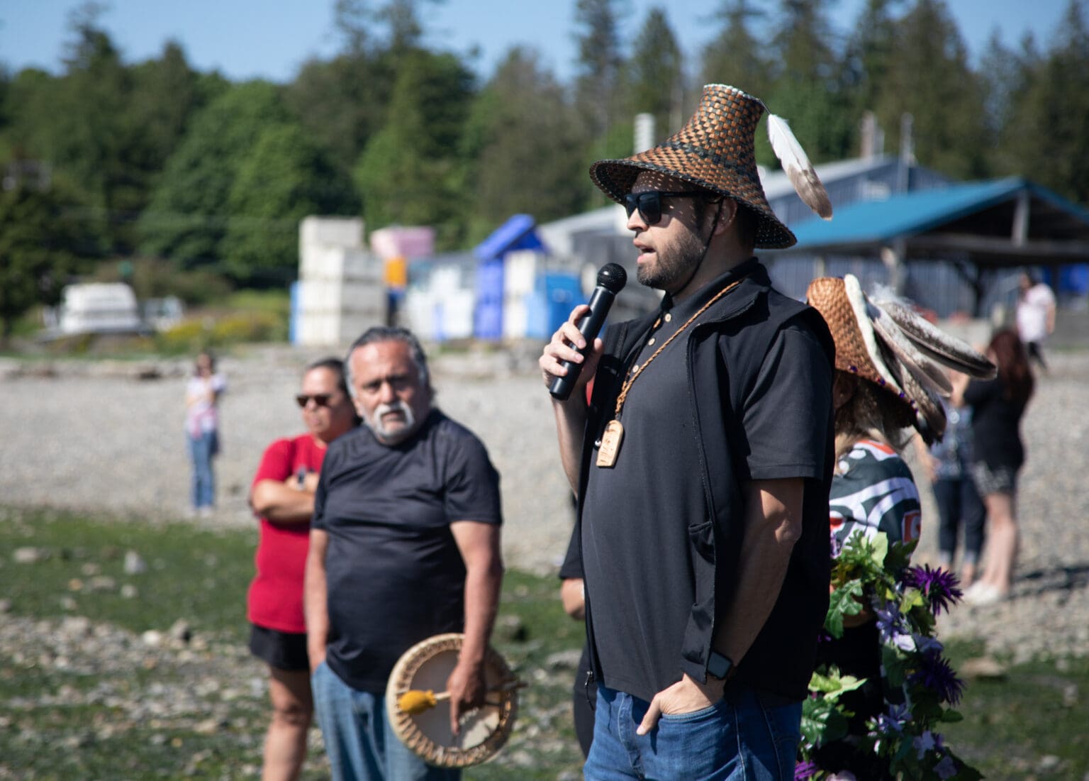 Tony Hillaire, chairman of the Lummi Nation, speaks with a microphone in hand and with a traditional hat on.