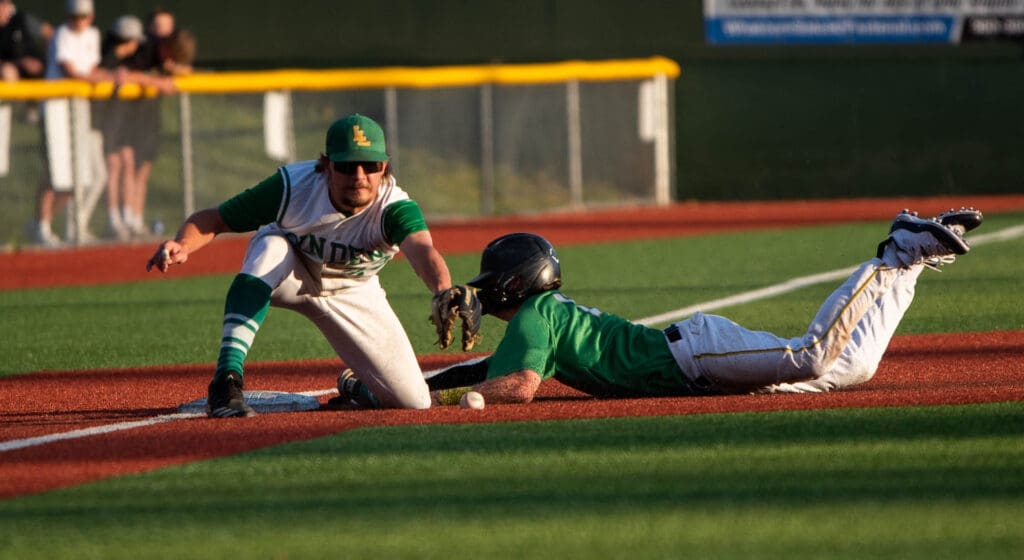 Senior third baseman Lincoln VanDiest tries to catch the ball in time to tag out Tumwater's Brayden Oram who dived