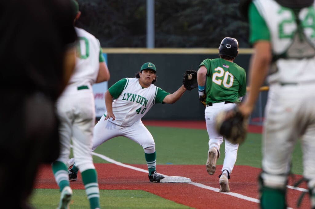 Senior first baseman Jesus Ortiz leans to tag out a player running towards the base.