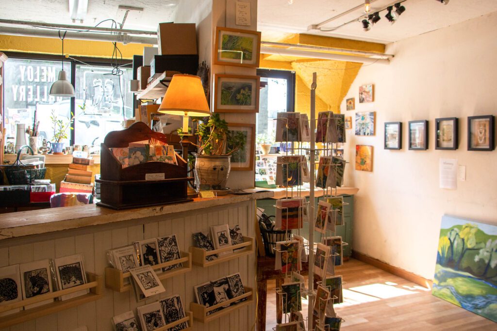 The inside of Meloy Gallery has many art pieces for sale, some framed and put on the walls.