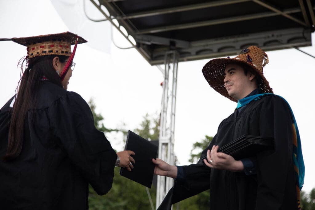 Brandon Morris — a member of the Lummi Nation and Tribal Governance and Business Management chair — hands out diplomas.