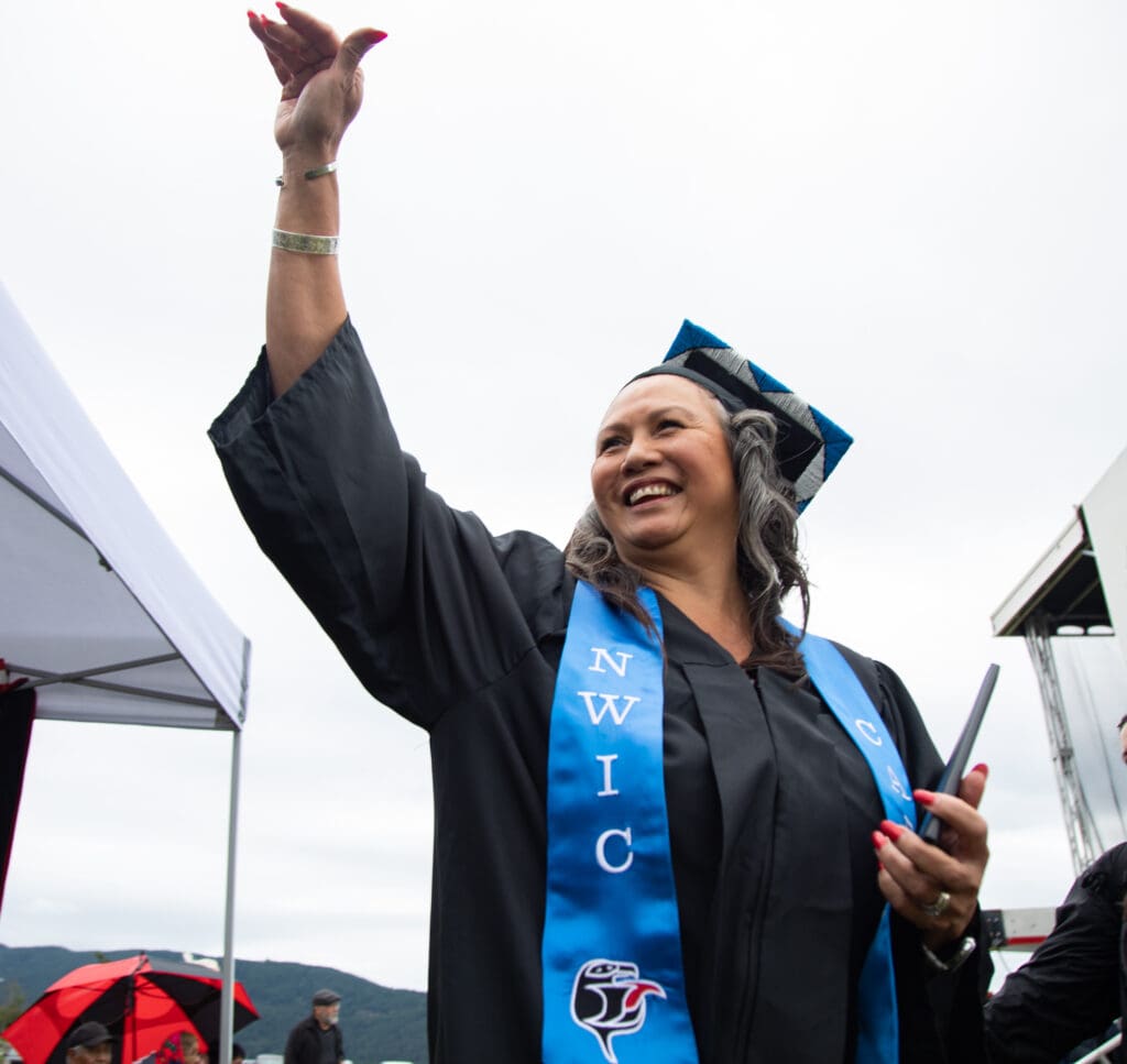 Carmen Cooper of the Nooksack Indian Tribe waves to supporters after receiving her diploma.