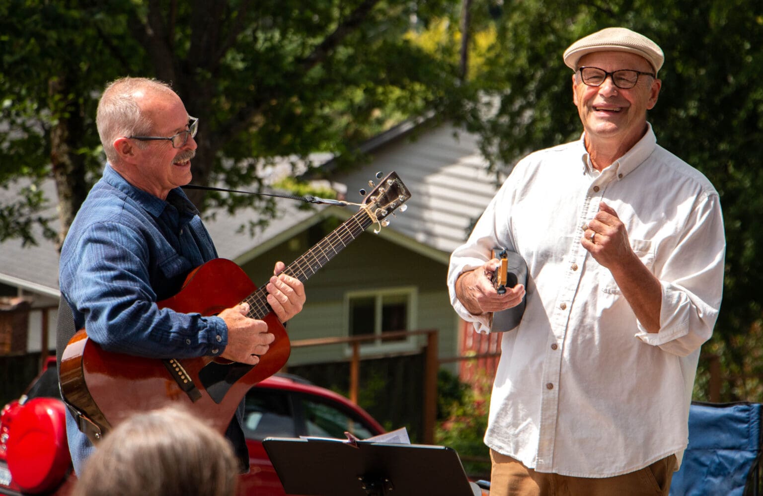 Mike Hall, left, and Paul Klein harmonize with the crowd as they hold their respective instruments, an acoustic guitar and a ukulele.