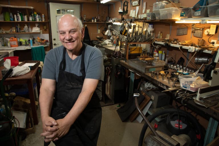 Dave Friedman sits in his home silversmith shop with a smile.