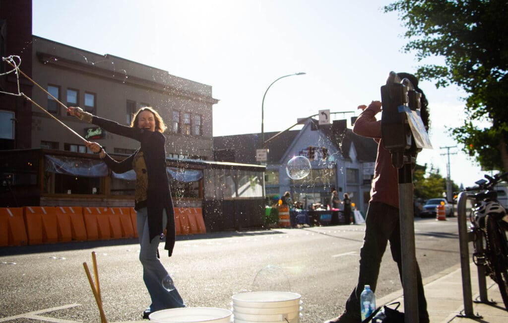 Ali Michelin, left, swings an arch of bubbles over her head as Emilio Lopata watches with admiration.