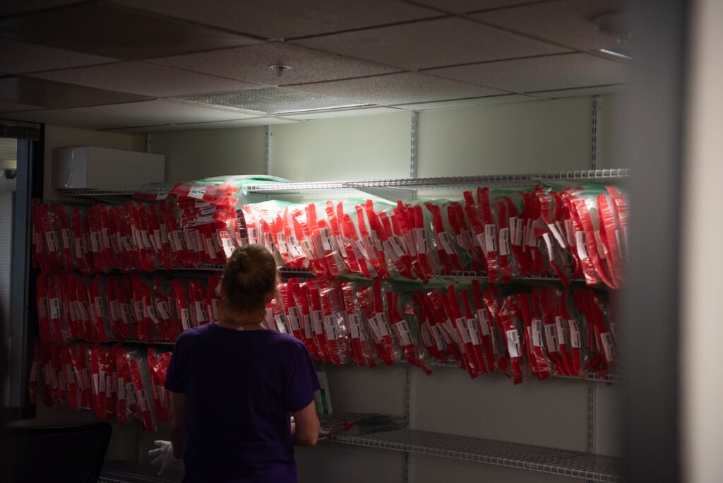 Election Supervisor Amy Grasher looks at shelves filled with approved ballots with red seals.