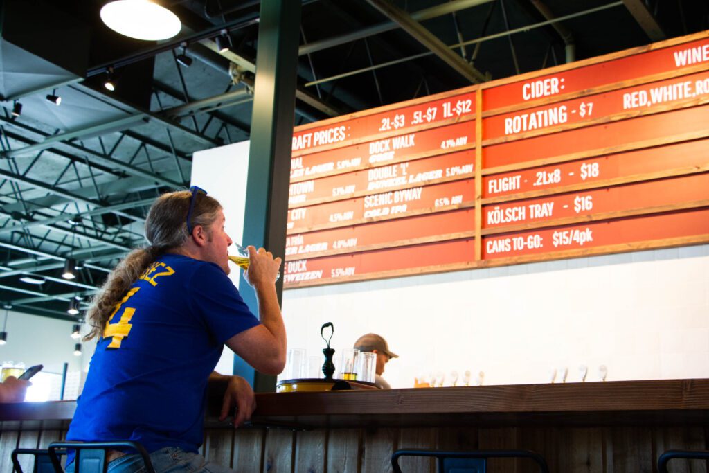 Kenny Austin drinks a beer at Larrabee Lager Co. while looking at the menu of draft, ciders, and wines.