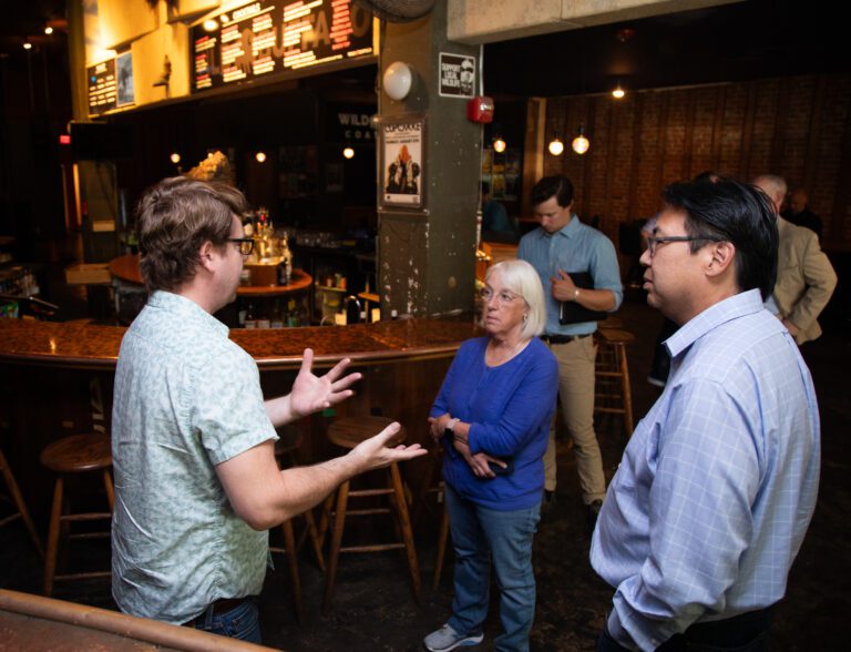 Part-owner of the Wild Buffalo, Craig Jewell, left, speaks with Sen. Patty Murray and Mike Fong as he gestures with both hands while he talks.