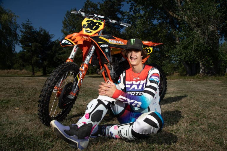 Jacob "JJ" Concannon sits next to his bright orange dirt bike to pose for a photo.