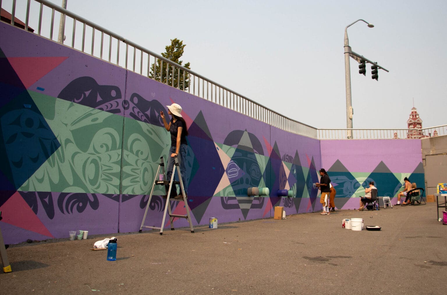 Indigenous artists help finish the multicolored Indigeversal mural.