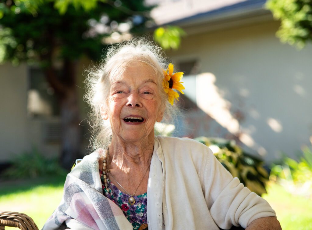 Darlene Little, with a sunflower in her hair, laughs as her daughter Laurie Lee Lewis retells a story.