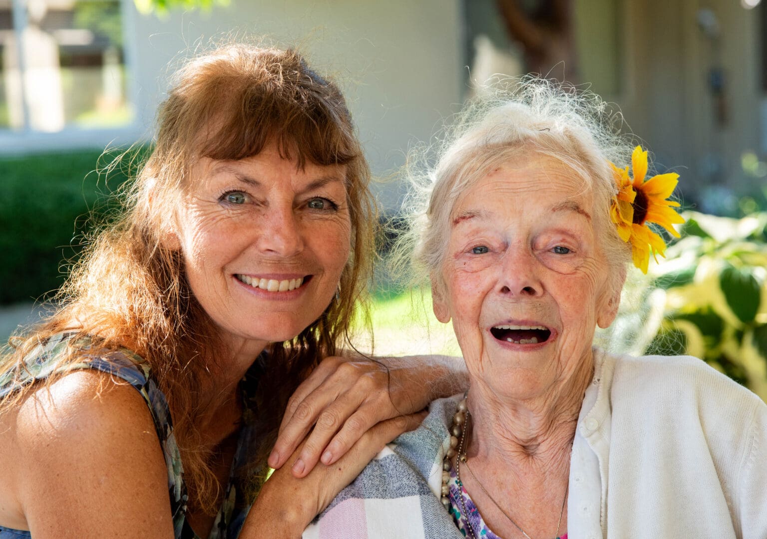 Darlene Little with a sunflower in her hair, right, smiles with her daughter, Laurie Lee Lewis.