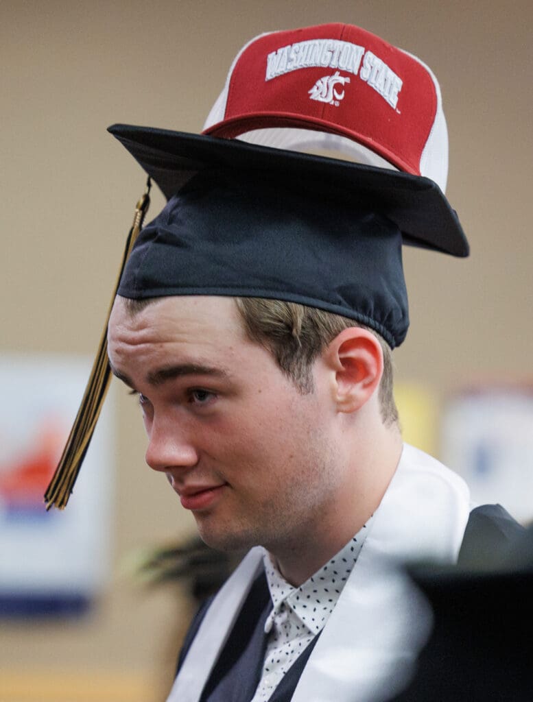 Carson Adams balances a friend's hat on his mortarboard before the graduation ceremony.