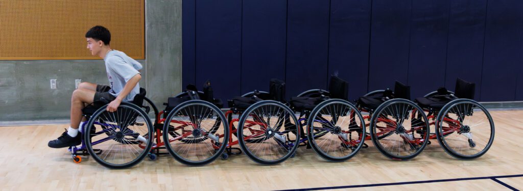 Reporter Andrew Foster tugs a line of wheelchairs behind him back to storage.