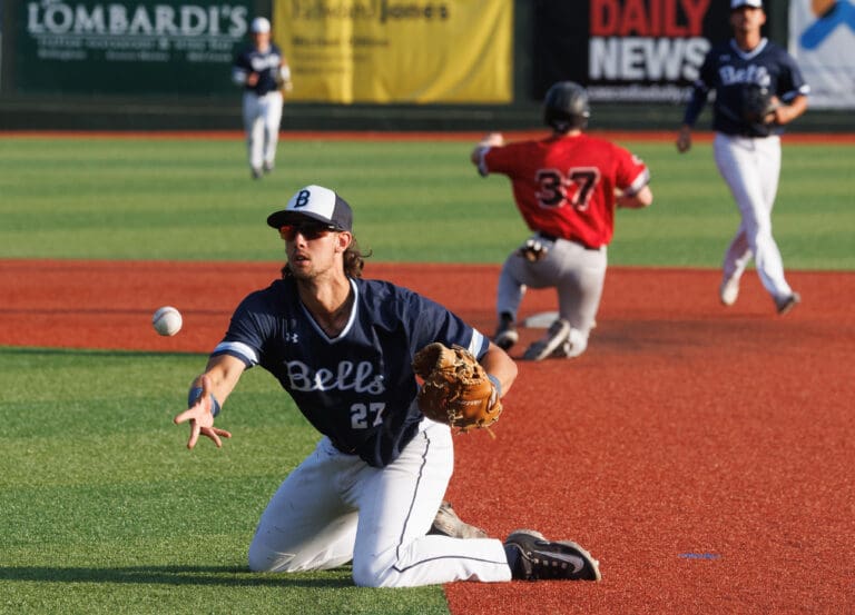 Yohann Dessureault makes an underhand throw while his knees are on the red and green grass.