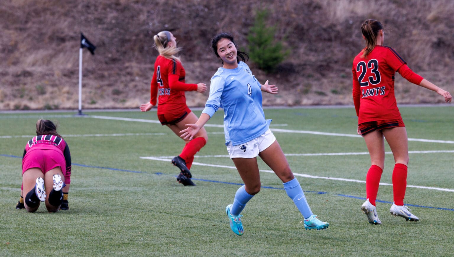 Western Washington University's Morgan Manalili turns toward her teammates in celebration as other players react in disappointment around her.