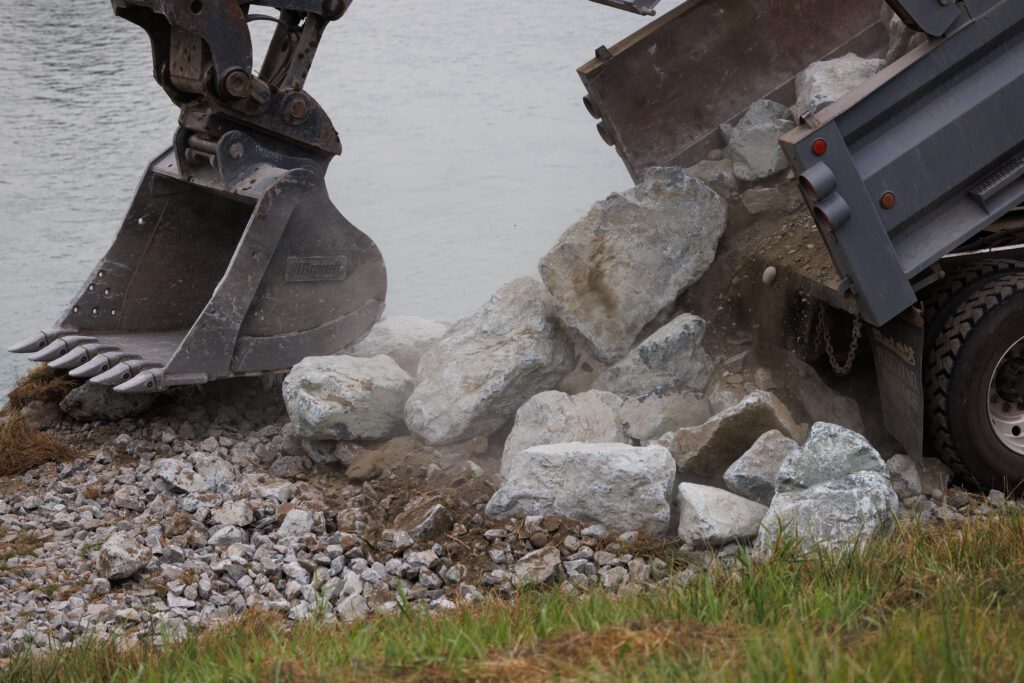 A ramp drops dirt and rocks next to an excavator.