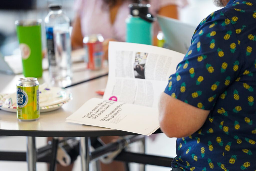 A training participant reads through materials on the Standard Response Protocol with other people with drinks and plates on the table.