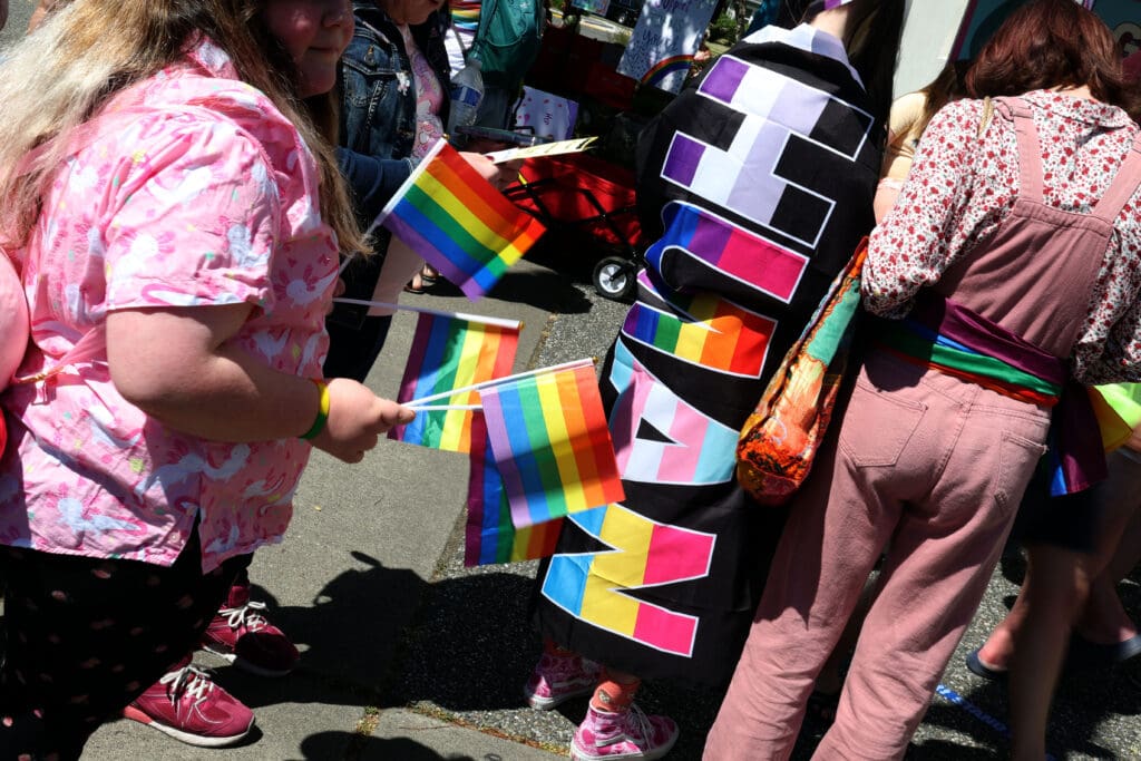 A festival goers wears a flag bearing the Pride colors and the word “human.”