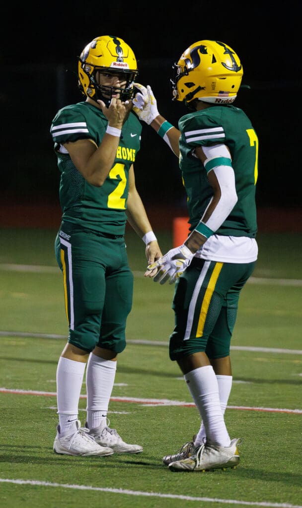 Sehome's Nolan Wright and Andre Watson end a celebratory handshake after Watson’s touchdown dressed in their team's signature green jersey.