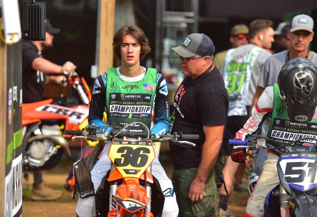 Jacob "JJ" Concannon, sitting on the dirt bike, talks with his father, Jaime, next to other attendees.