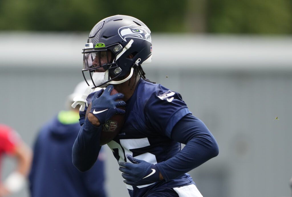 Seattle Seahawks running back Kenny McIntosh (25) holds a football close to his chest.