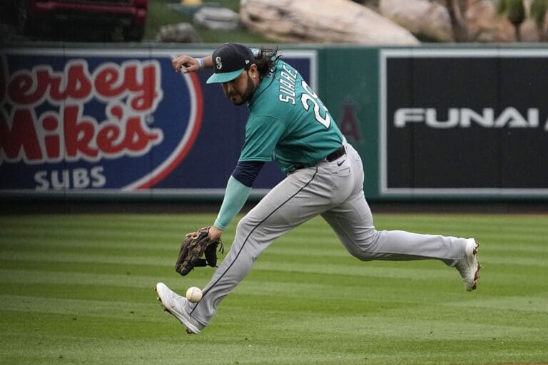 Seattle Mariners third baseman Eugenio Suarez fields a ball hit as he leans down to reach it.