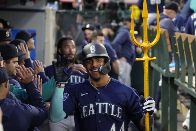 Seattle Mariners' Julio Rodriguez waves a hand as he holds the golden trident with his free hand.