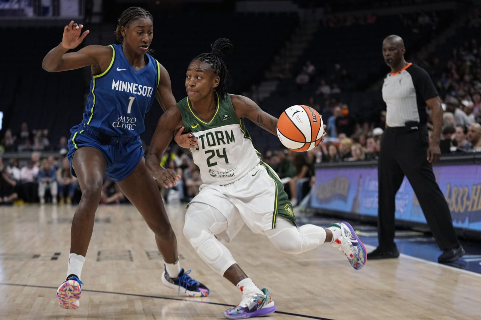 Seattle Storm guard Jewell Loyd (24) turns sharply towards the basket as a defender hovers his arm above him to predict a block.