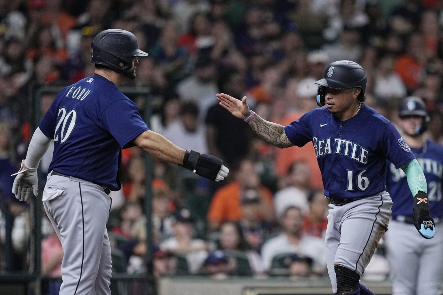 Seattle Mariners' Mike Ford (20) and Kolten Wong (16) celebrate with a low-five.