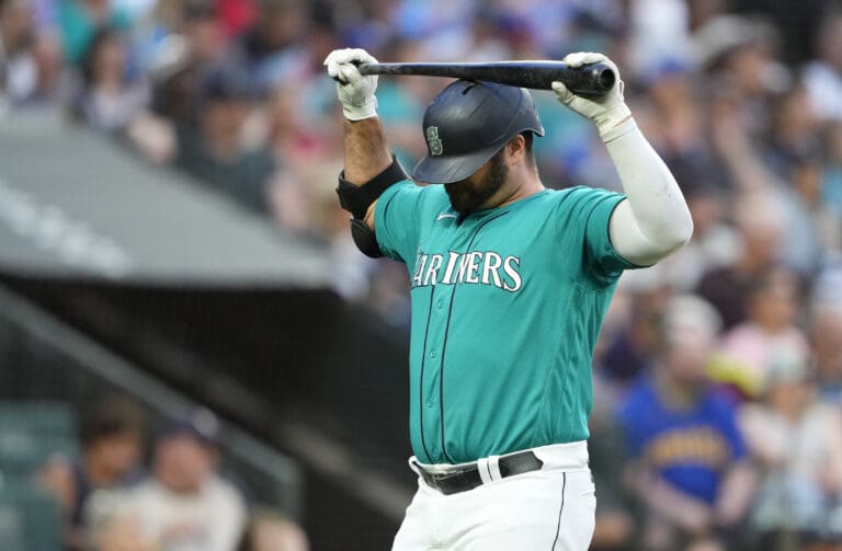 Seattle Mariners' Mike Ford holds his bat above his head in reaction after striking out.