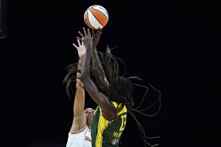 Seattle Storm center Ezi Magbegor shoots over Phoenix Mercury forward Brianna Turner mid-air with parts of his hair flying around.