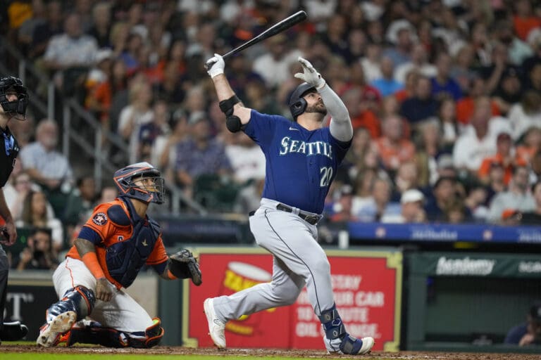 Seattle Mariners' Mike Ford, right, watches the ball he just bat as onlookers do the same in reaction.