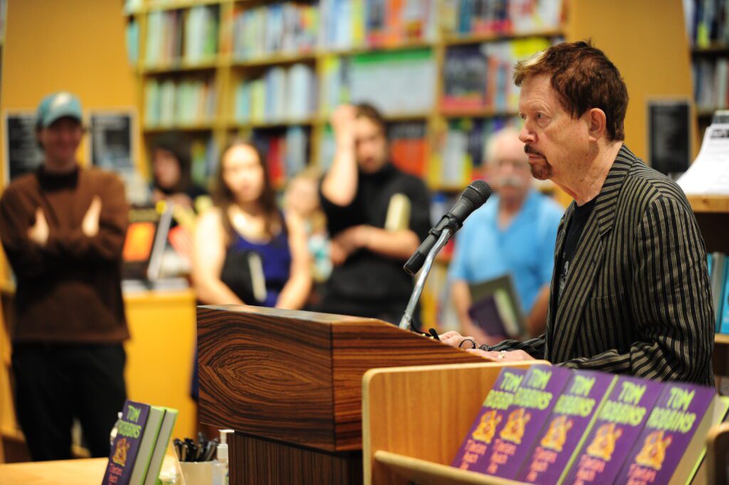 Tom Robbins reads from his memoir "Tibetan Peach Pie" at Powell's Books as attendees listen surrounding him.