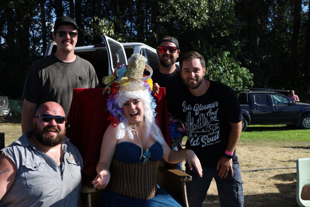 BrewFest Queen posing with attendees for a photo on a throne-like chair.