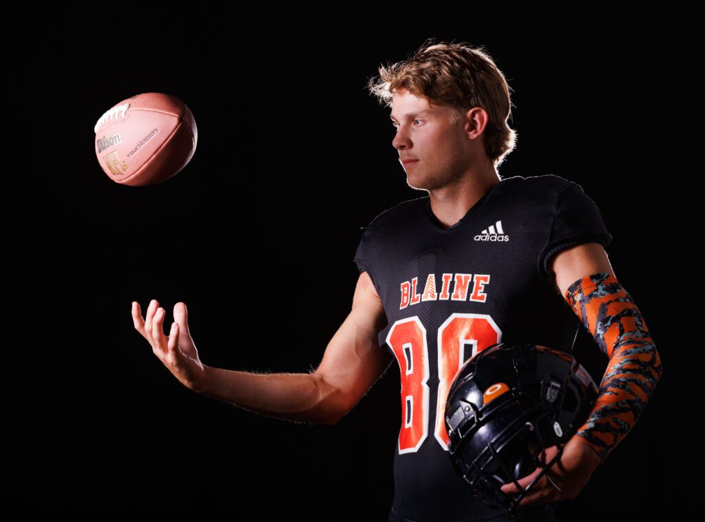 Blaine football tight end and edge rusher Conner Dalry tosses a football with one hand and holds his helmet with the other.