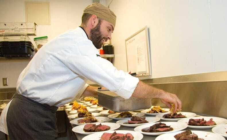 Charles Claassen adds garnishes to his dishes at the Environmental Learning Center dining hall.