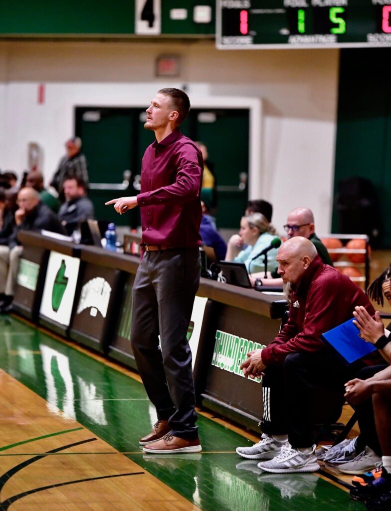 Alex Sommerfield watches from the sidelines as other attendees watch seated.