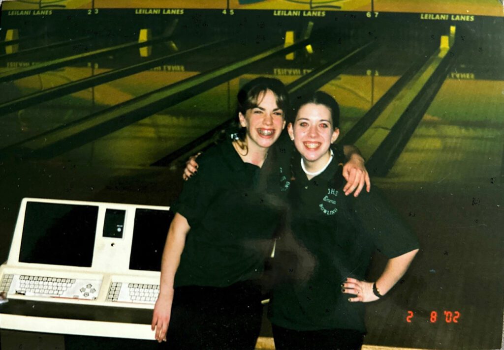 A young girl and her teammate pose for a photo in an old bowling alley.