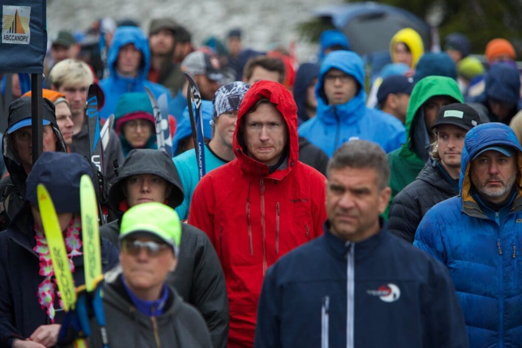 Downhill and cross-country skiers and runners congregate in a crowded huddle.