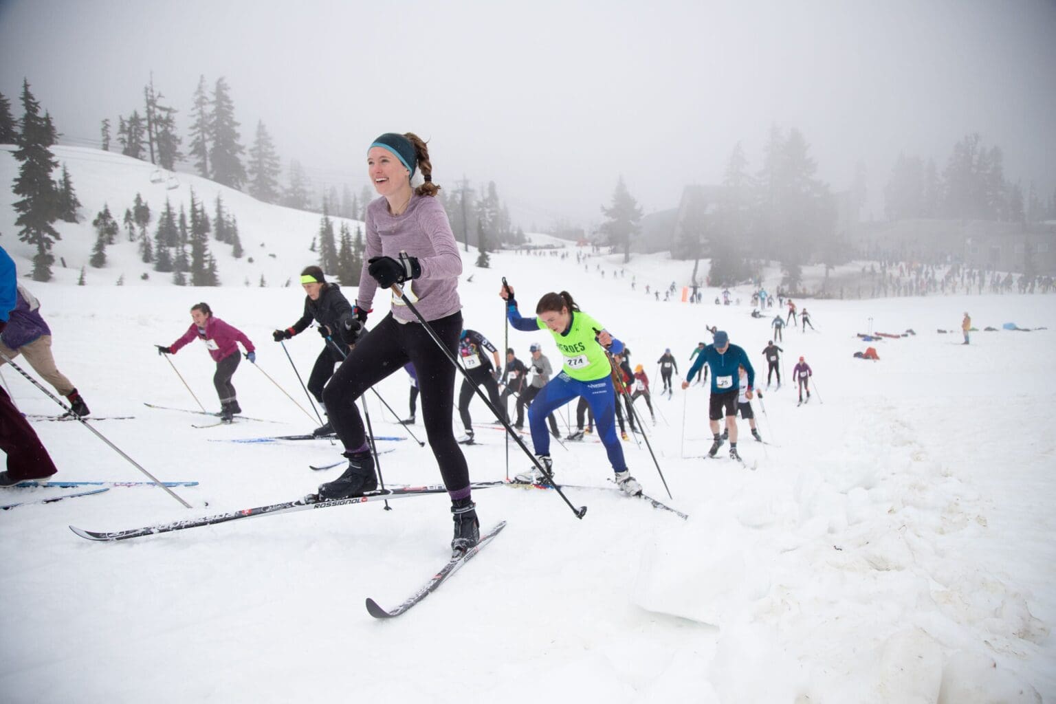 Elizabeth Watters from The Lost Canoe team climbs a hill in the cross-country ski leg followed by a long trail of competitors making their way up the hill.