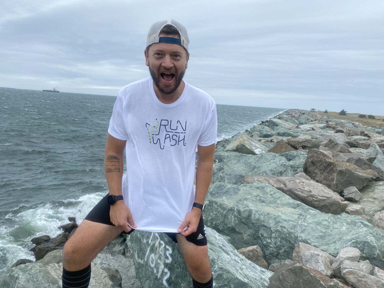 Marcus Nuckolls, an eighth-grade teacher at Fairhaven Middle School, poses for a photo by pulling his shirt down to show the Run Wash logo.