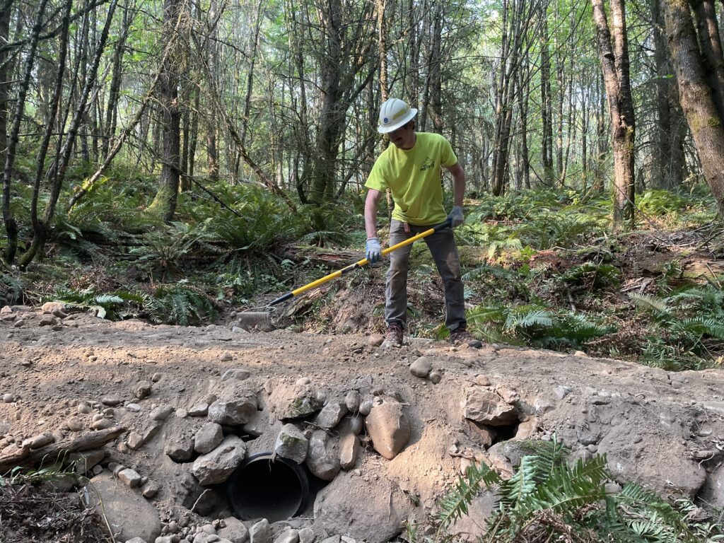 Finn Hopper, a DNR state lands forester, rakes a section of dirt over a large pipeline.