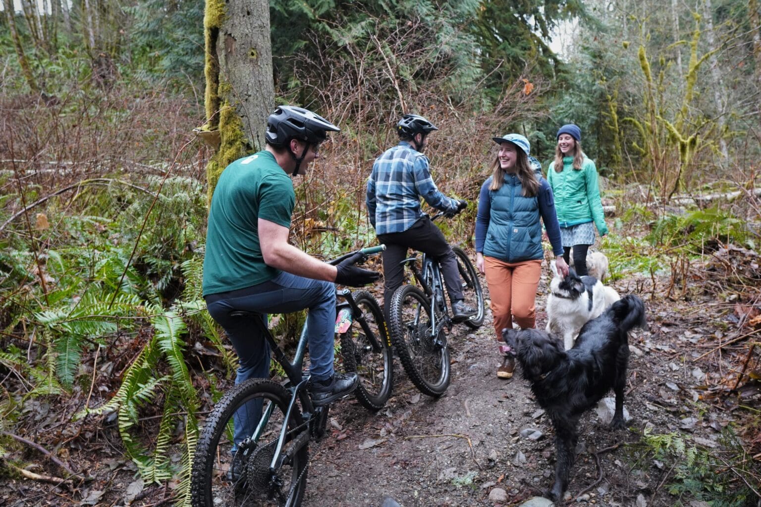 Mountain bikers Jeff Bowers and Henry Lawrence stop along a narrow path of the Y Road Trail to give way and chat with dog walkers Sarah Finger and Michelle Cousins.