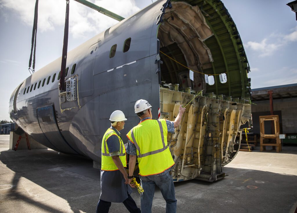 Brian Wilson, left, and Ron Fronheiser survey the fuselage after it is placed as one points with a measuring tape.