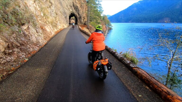 Bikes head towards the two tunnels on the Spruce Railroad Trail leg of the Olympic Discovery Trail with Lake Crescent next to the road.